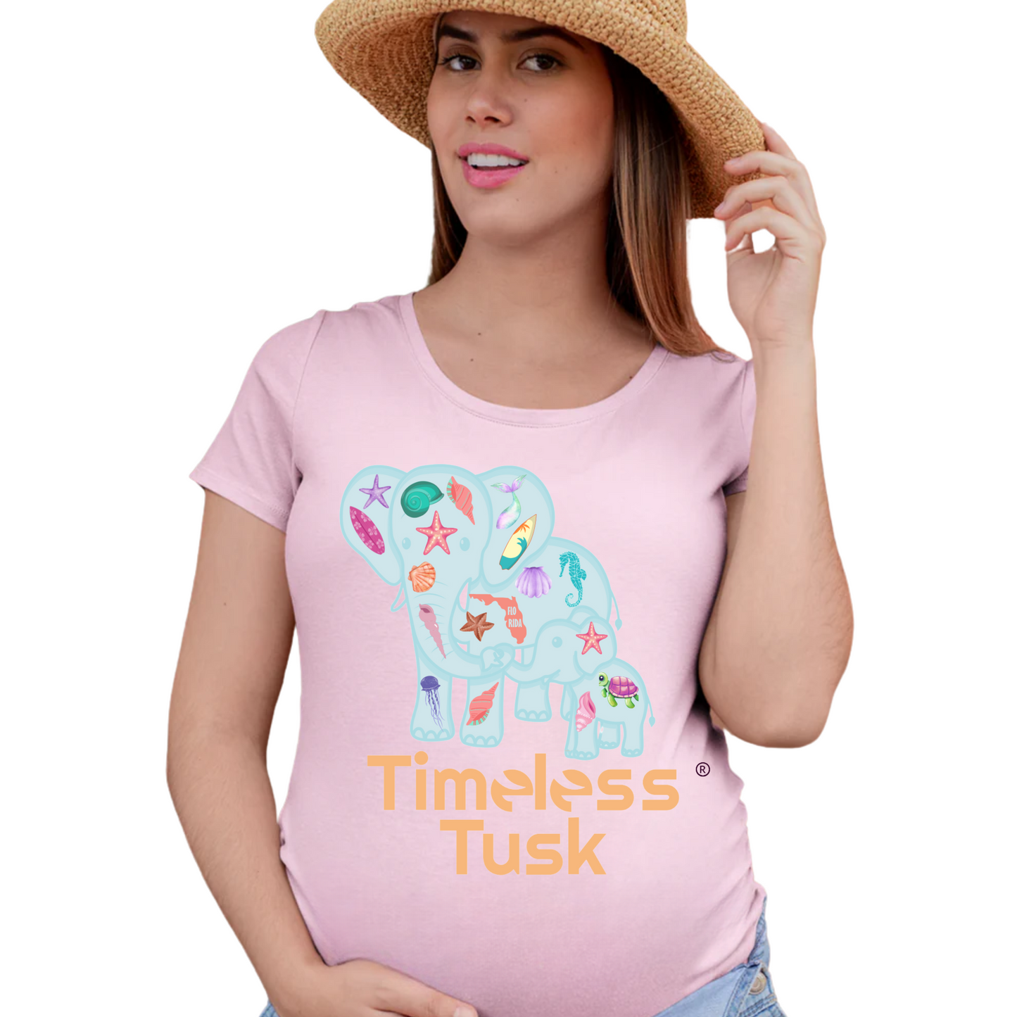 Pregnant woman wearing the elephant maternity shirt, standing near the ocean, embracing coastal vibes.